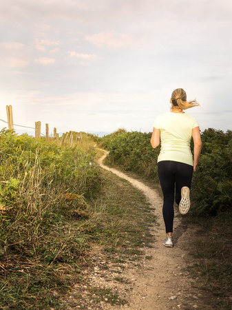 Woman running along a path at sunset