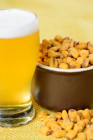 roasted and salted corn in ceramic pot over yellow jute and with a glass of cold beerの写真素材