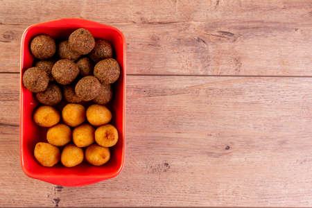 Brazilian fried savory snack mix with coxinha and fried kibbeh in red bowl.の写真素材