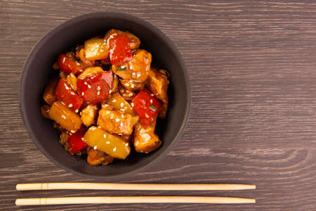 chess chicken in black bowl on wooden background - chinese food.の写真素材