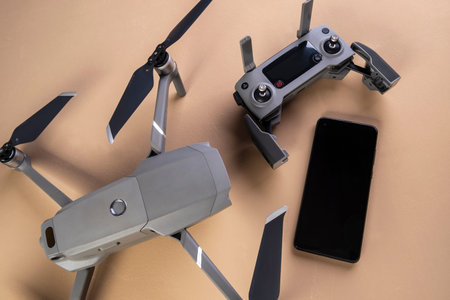 DJI mavic 2 pro drone, its controller and a smartphone on brown background.