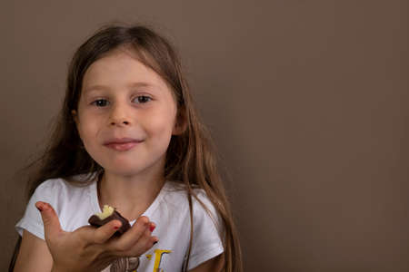 beautiful little girl eating chocolate on brown background.の写真素材
