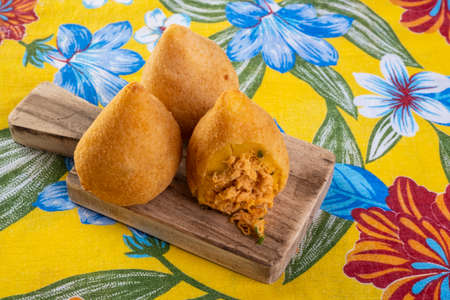 fried coxinha on a cutting board on fabric with flower prints.の写真素材