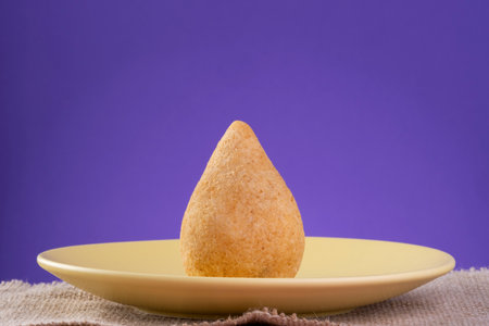 Fried drumstick on a yellow plate with a purple background.の写真素材
