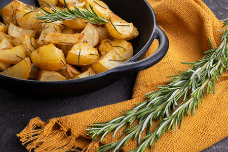 baked fried potatoes with rosemary, coarse salt, olive oil and spice paprika in iron skillet.の写真素材