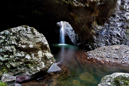 Dark cave full of water and waterfallの写真素材