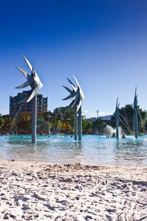 Deserted section of the beach and Fish Sculptures at the Esplanade swimming lagoon in Cairns with bathers visible in the distance in the waterのeditorial素材