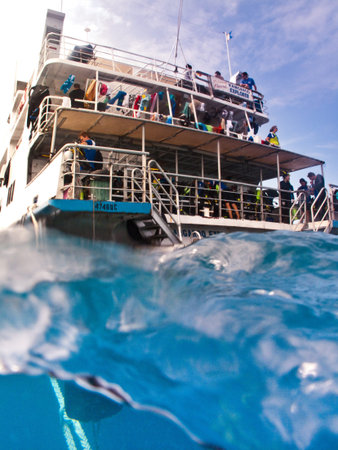 View from the water of the back of a tourist dive boat with people on the decks in mid oceanのeditorial素材