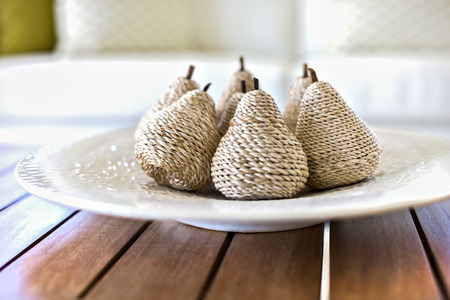 Closeup of a gift item decoration made by a thick thread spun around a wooden stick on a white ceramic plate, There are wooden bars under the dish and should be tabled, background is mixed white and blurredの写真素材