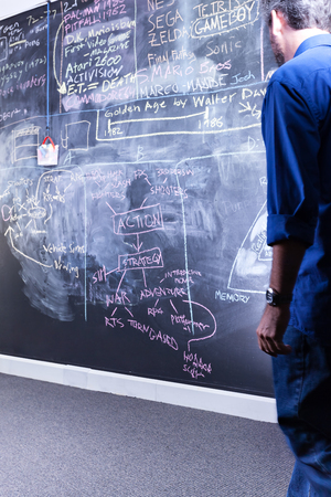 Guy with a blue dress looking at a blackboard in a classroom or a labの写真素材