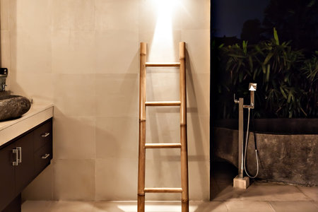 Bamboo ladder near the wall in a washroom beside garden with illumination at nightの写真素材