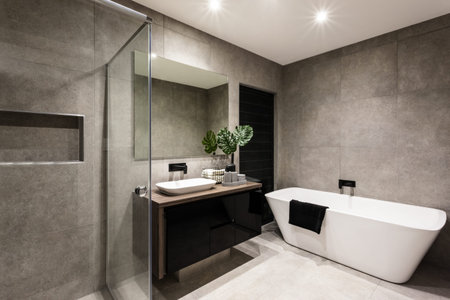 Modern bathroom with a shower area and bath tub including a wall mirror beside a fancy plant near a...