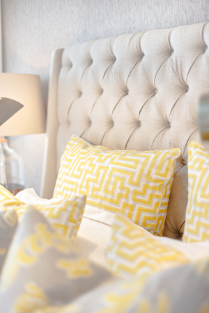 Yellow pillows with a maze art on the modern  bed closeup with a working table lamp in a luxury houseの写真素材