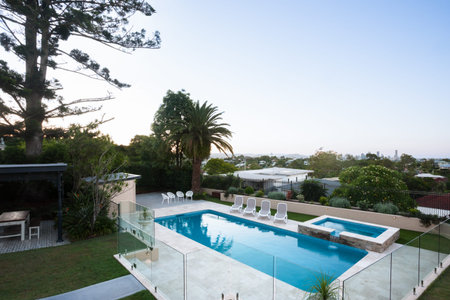 Modern swimming pool area view from a high angle shot which covered with glass panels and tress...