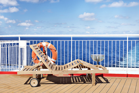 Wooden chair on ship outside floor, sky is colorful and have white clouds, sunlight arround the area.の写真素材
