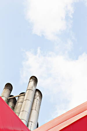 Factory smoke pipes with blue sky, sunlight arround the area, natural view closeup, daytime scene, walls are red color, clouds are white.の写真素材