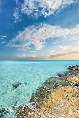 Blue sea and under the white clouds at evening view, the water is clear and covered the yellow and rough groundの写真素材