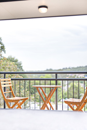 Close up of wooden chair and table near garden, comfortable furnitures with designs, walls are white color, outside area of a apartment.の写真素材