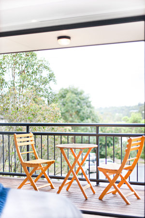 Wooden chairs near tree view, comfortable furnitures with designs, walls are white color, outside...