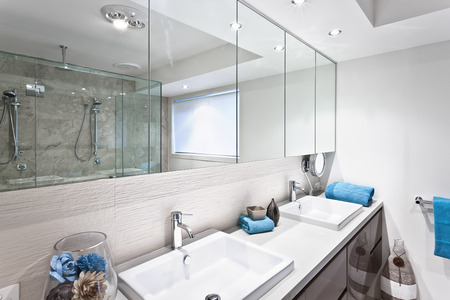 Modern bathroom with faucets and wide mirrors of luxury house or hotel and ornamental itemsのeditorial素材