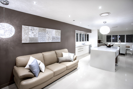 Modern living area with sofa and pillows illuminated by hanging lamps with white wallsのeditorial素材