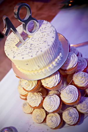 Delicious tower birthday cake with cupcakes in the base and a white creamy cake on top with digits 18.の写真素材
