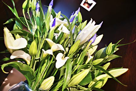 White flowers with green leaves placed together in a well lit room of with a lamp hanging onto the flowersの写真素材