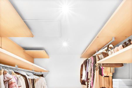 Modern clothing store with wooden shelves and lots of dresses for man and woman, the area is illuminated dress store in a modern house or storeの写真素材