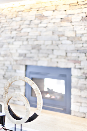 Round fancy item on the table beside a blurred stove, stone wall in a luxurious house with the sunlight illuminating, the circle is made in blocks with a hole in the middleの写真素材
