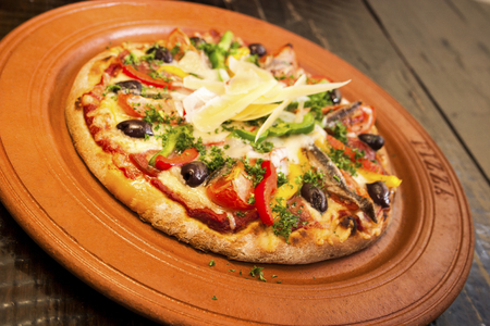 Hot and fresh pizza with cheese slides, ceramic plate with food on wooden table, luxury hotel or house inside room, lights and colors are perfect.の写真素材