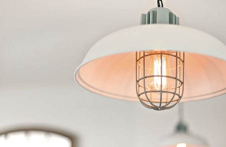 Hanging lamp with light bulb including filament and a metal cable cover flashing with a white...