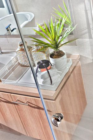 Modern washroom, shower area with a mirror and fancy items including a perfume bottle and soap near...