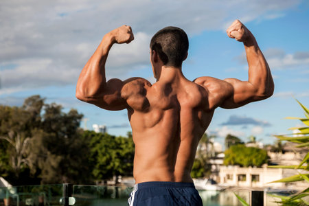 Fitness trainer standing with hands up, outside area near lake and houses, natural trees give beauty...