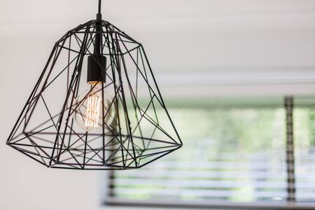 Close view of a contemporary cage design ceiling light with the bulb switched onの写真素材
