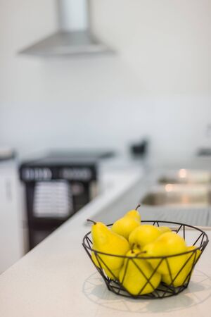 A view of a stylish fruit basket with ripe pears kept on a kitchen shelfの写真素材