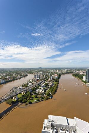 Lake with trees and bridge arround city , buildings are huge and designed with modern technology, trees are very colorful with green, river is mud color, sky is blue with white clouds.の写真素材