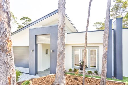 Valuable huge trees near home entrance, natural garden with luxury house outdoor, sunlight arround the area, sky is white color.の写真素材
