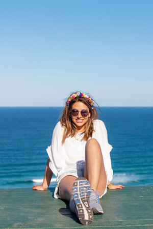 Fashionable caucasian girl enjoying the weekend at the beach. A cute young lady sitting near the...