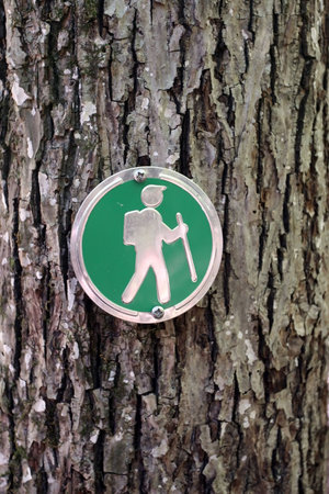 Close up of a hiking trail guide sign posted on a tree. の写真素材