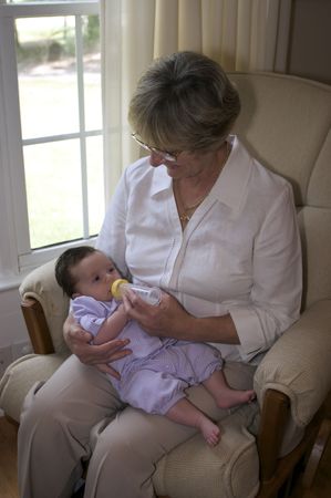 Close in shot of a grandmother feeding a bottle to a baby girl.の写真素材