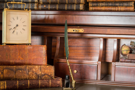 old clock on shelf with old books and penの写真素材