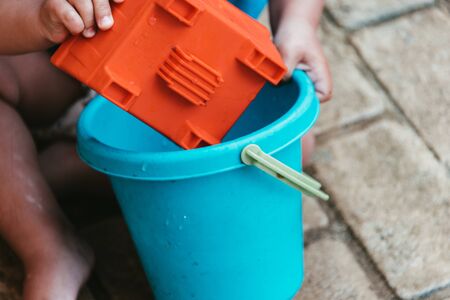 little boy playing with bucket and water at home confinement covid19の写真素材