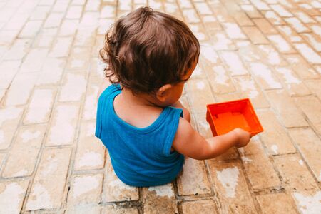 little boy playing with bucket and water at home confinement covid19の写真素材