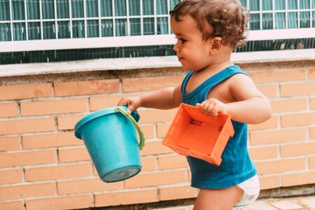 little boy playing with bucket and water at home confinement covid19の写真素材
