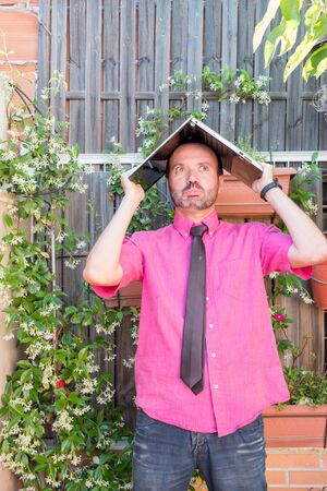 Middle-aged man teleworking in his backyard fuchsia shirt with tie and dark jeansの写真素材