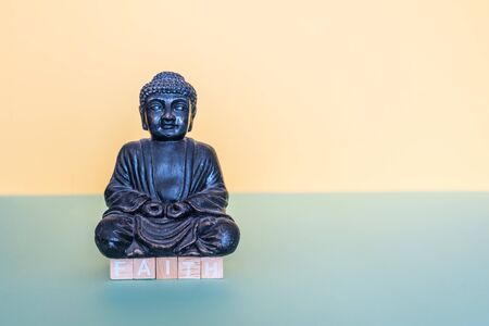with wooden stamps the word faith is formed below the buddha figureの写真素材