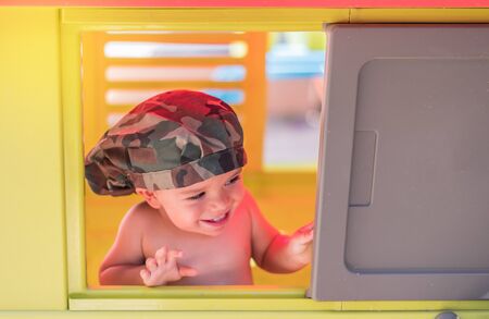 child playing in toy house leaning out the window and with the background out of focusの写真素材