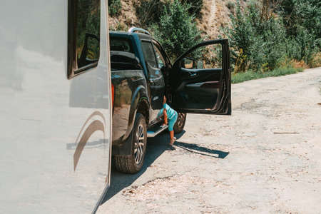 little boy getting into a car with a caravanの写真素材