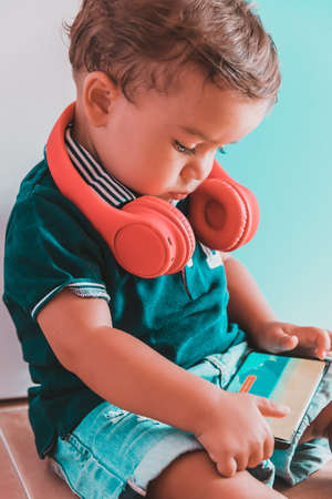 portrait child listening to music with headphones on brick wallの写真素材