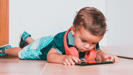 portrait child listening to music with headphones on brick wallの写真素材